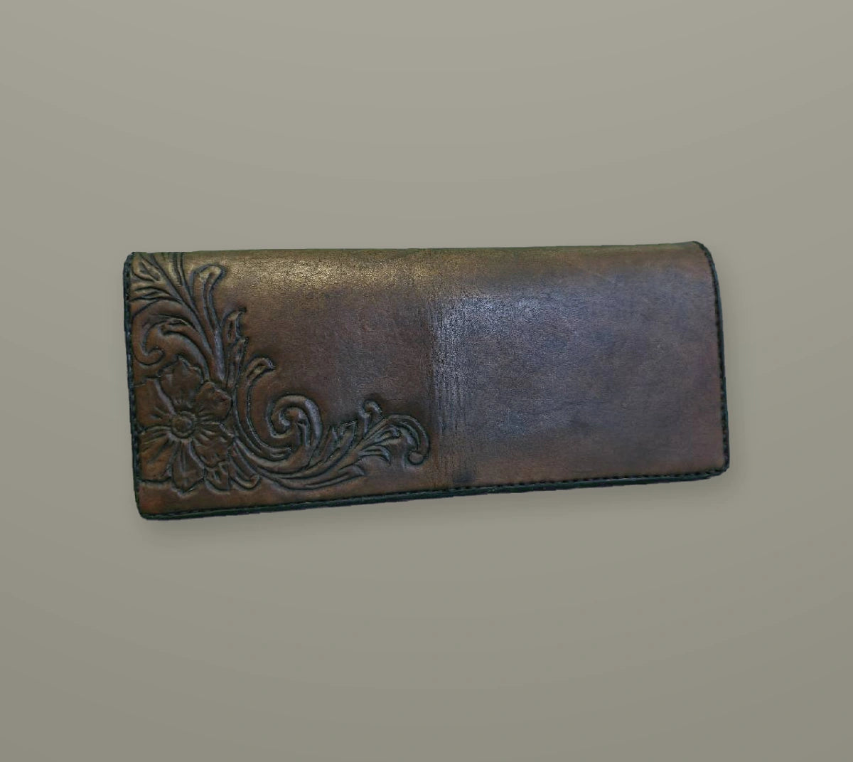 Finished long leather wallet with floral tooling on a muted slate background